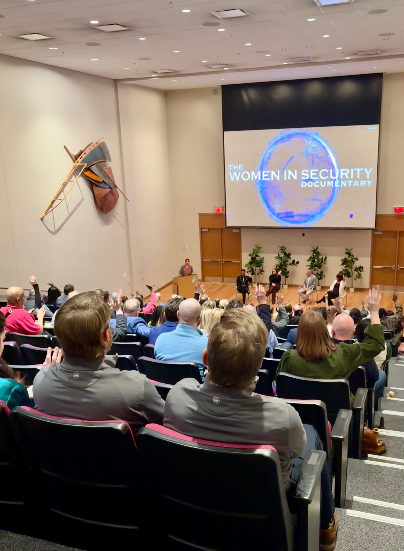 A seated audience raising their hands during a discussion following a screening.